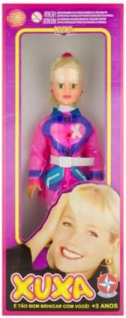 Boneca Xuxa - Brinquedo Estrela Oficial | Seus cabelos loiros, presos em um rabo de cavalo com franjinha, combinam com o look fashion em tons de rosa e azul.